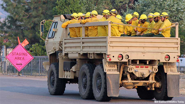 Firefighters in an open National Guard vehicle.