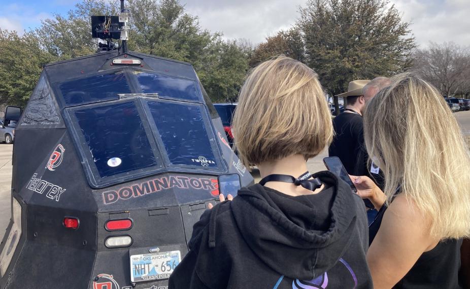 Two women take photos of a storm chasing sensor. 