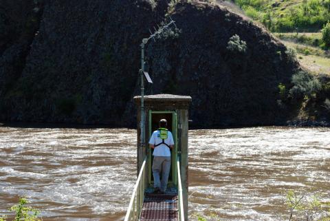 A photo of a hydrologic tech entering a streamgage.