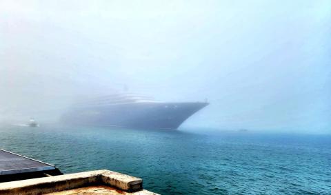 A photo of a ship sailing in the fog. 